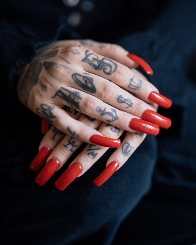 tätowierte Hände mit roten Fingernägeln