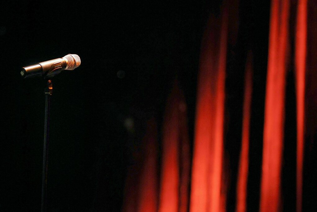 Ein Mikrofon steht in einem Theater vor einem roten Vorhang