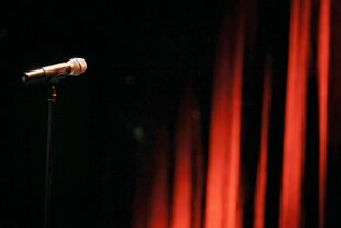 Ein Mikrofon steht in einem Theater vor einem roten Vorhang