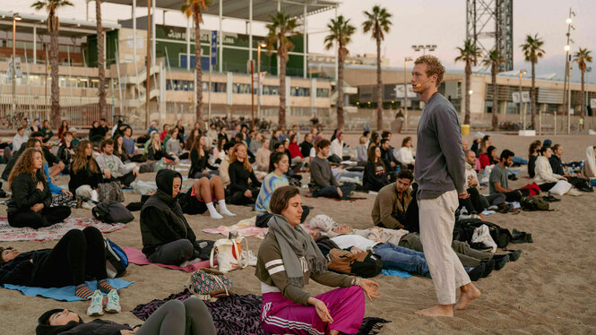 Eine Person leitet eine Yoga-Gruppe am Strand.