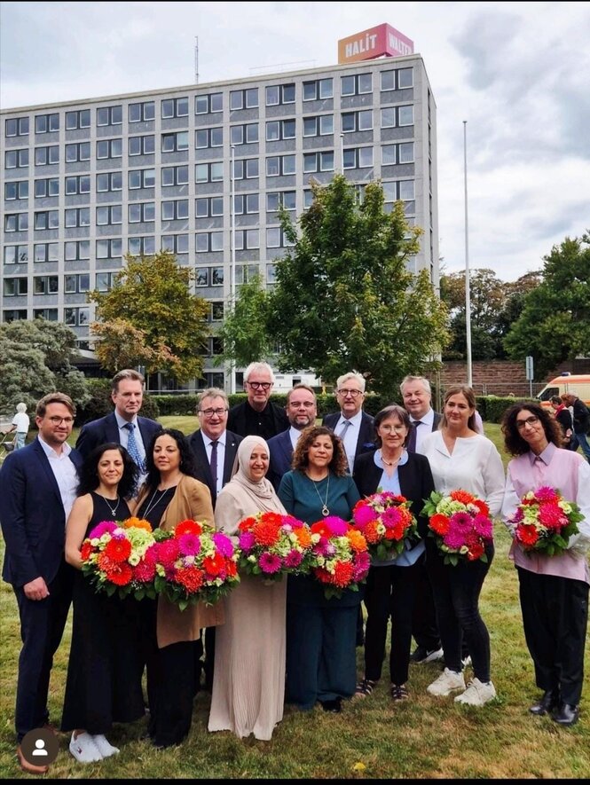 Menschen mit Blumensträußen stehen vor dem Gebäude des Regierungspräsidiums