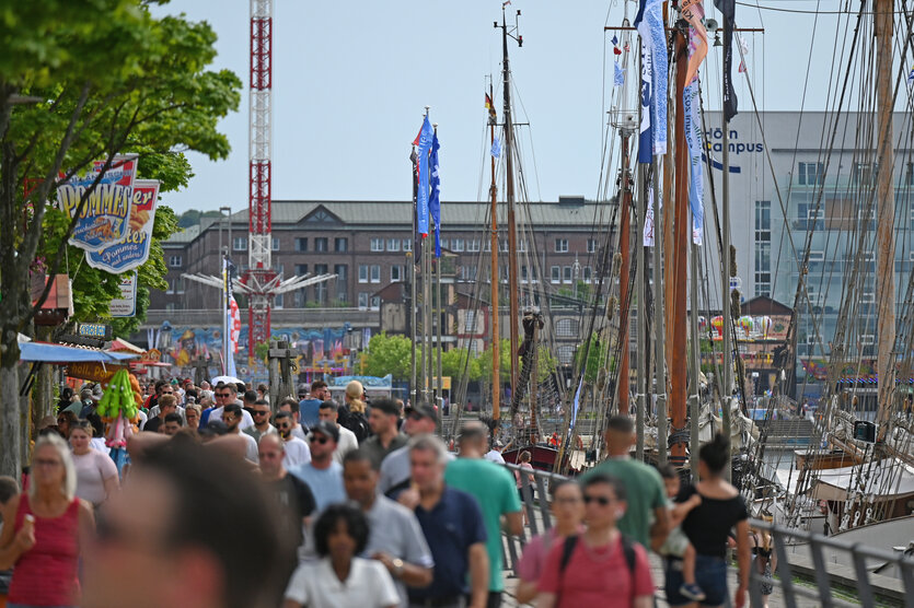 Menschen schlendern in der Kieler Woche am Hafen entlang
