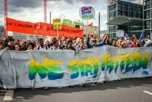 Demonstrant:innen hinter einem Transparent, auf dem 