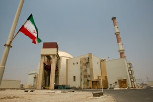 Eine Iranische Flagge flattert vor dem Reaktorgebäude des Kernkraftwerks Buscher.