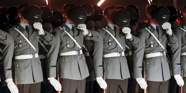 Vier Soldaten halten sich die Helme vors Gesicht.