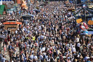 Perspektive auf eine große Menschenmasse zwischen den Ständen und Bierzelten des Oktoberfestes