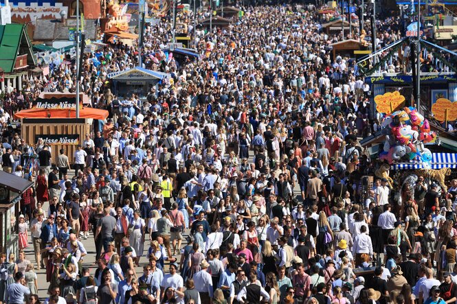 Perspektive auf eine große Menschenmasse zwischen den Ständen und Bierzelten des Oktoberfestes