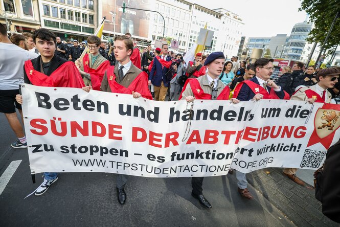 Mehrere junge Männer halten ein Transparent in die Höhe, auf dem steht: "Beten und handeln, um die Sünde der Abtreibung zu stoppen"