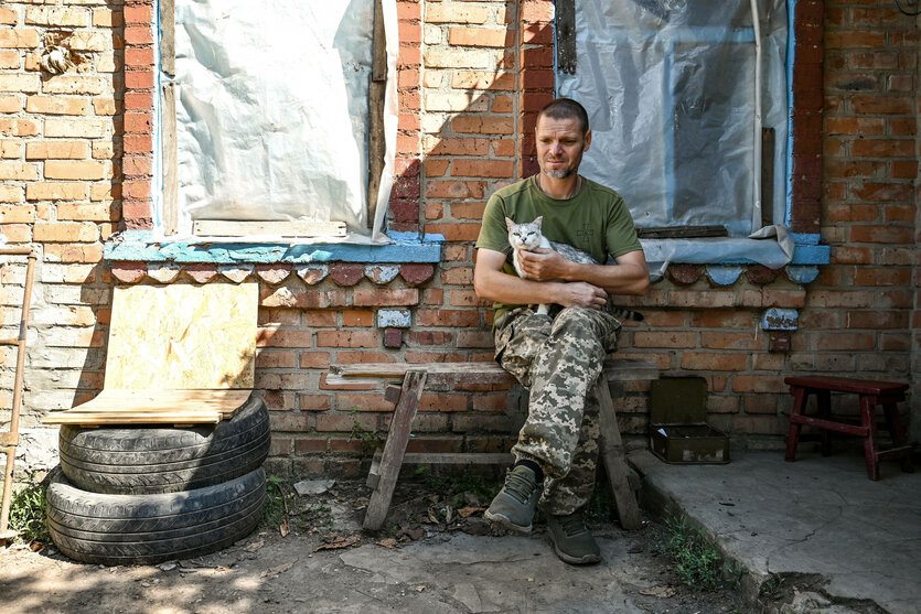 Soldat sitzt mit Katze auf dem Arm