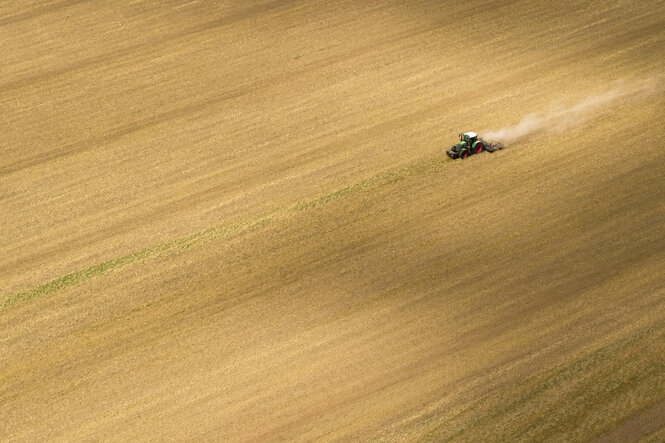Ein Landwirt fährt mit einem Traktor und einer Egge über ein Feld in der Region Hannover.