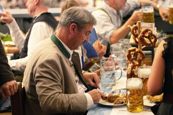 Markus Söder (CSU), Ministerpräsident von Bayern, isst bei der Eröffnung des Oktoberfestes im Schottenhamel-Festzelt Fleisch von einem Teller.