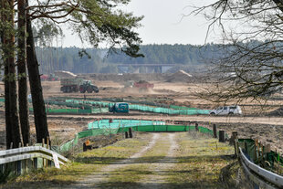 Eine Straße führt auf eine große Waldlichtung, Zugmaschinen transportieren Abraum ab.