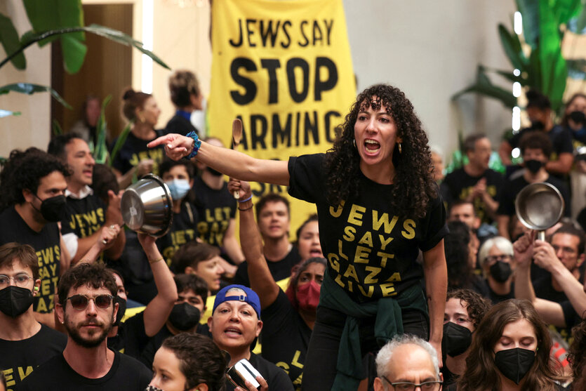 Aktivisten sitzen auf dem Boden, eine Frau steht mit Megafon in der Hand - alle tragen schwarze T-Shirts mit der Aufschrift: Jews say let Gaza live