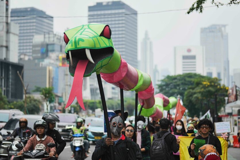 Umweltaktivisten führen während einer Kundgebung in Jakarta, Indonesien, eine Schlangenfigur vor sich her