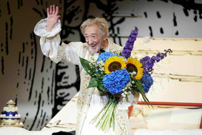 Didi Hallervorden verkleidet auf einer Bühne mit Blumen in der Hand