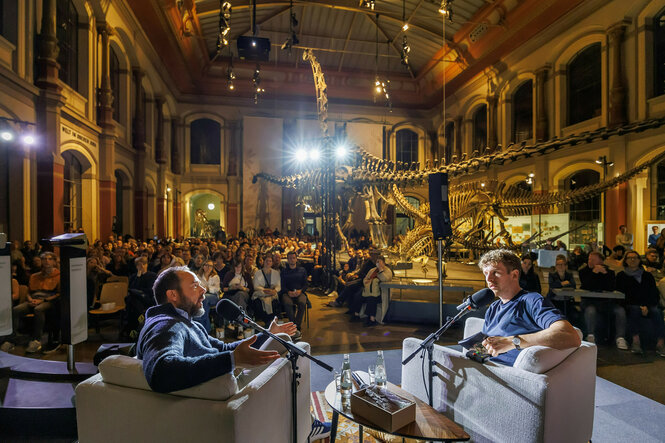 Zwei Personen unterhalten sich auf einer Bühne im Berliner Naturkundemuseum