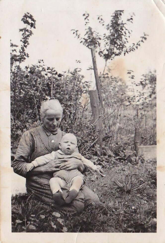 Ein SW-Foto zeigt eine Frau mit einem Kind auf ihrem Schoß