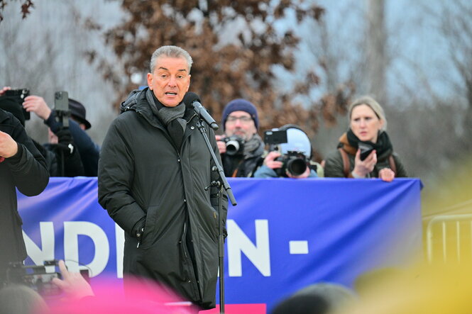 Michel Friedman auf einer Kundgebung vor einem blauen Transparent