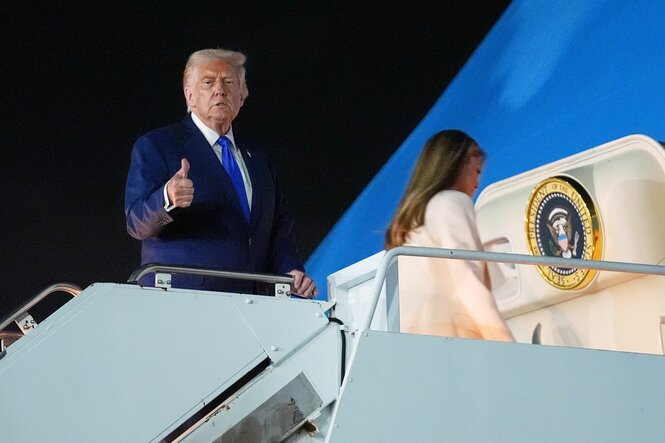 Trump steht am Eingang zum Flugzeug und hält einen Daumen hoch