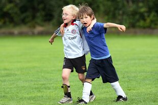 Zwei Jungen im Fusballtrikot umarmen sich