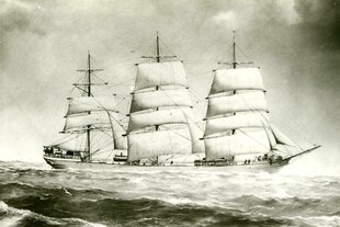 Ein historisches Schwarz-Weiß-Bild eines Segelschiffs mit mehreren Masten, das auf stürmischer See fährt