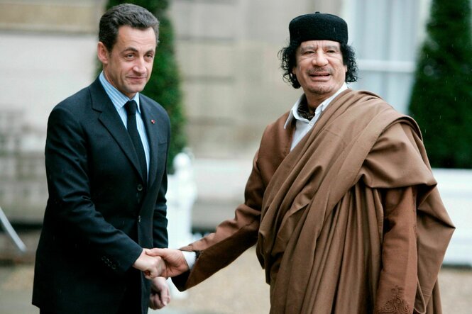 Nicolas Sarkozy begrüßt Moammar Gadhafi, der in ein braunes Gewand gehüllt ist