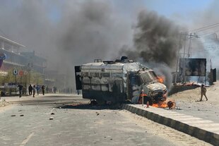 Ein ausgebranntes Fahrzeug qualmt auf einer Straße vor sich hin