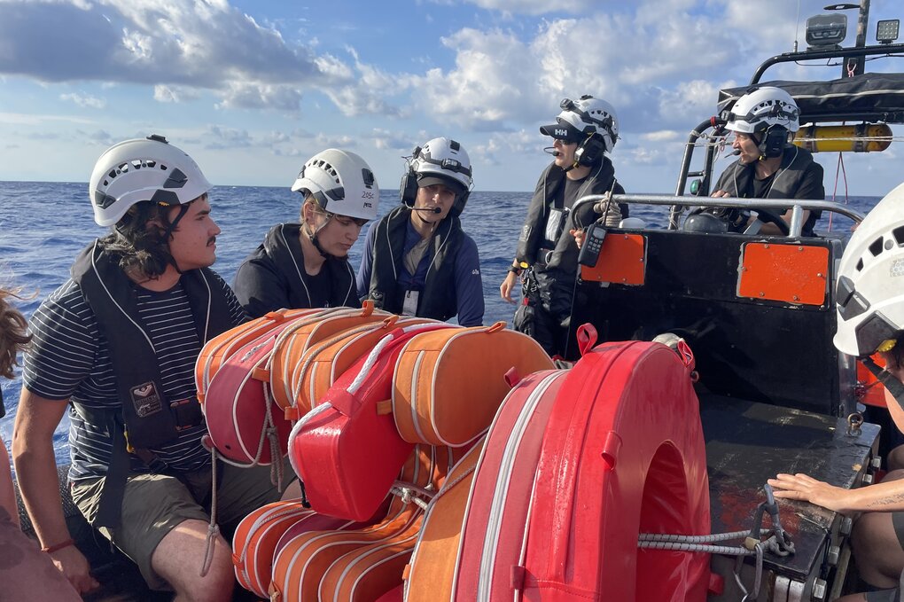 Menschen mit Rettungswesten und Helmen auf einem Boot