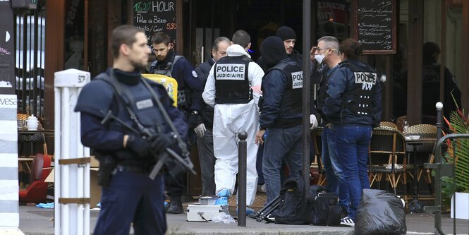 Polizisten mit Maschinengewehr vor einem Restaurant