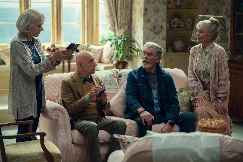 Drei Senior*innen sitzen auf einem Sofa, eine Person steht links daneben