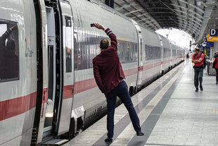 Ein Zugbegleiter zeigt das Signal zur Abfahrt