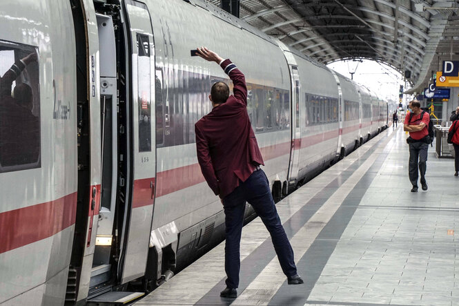 Ein Zugbegleiter zeigt das Signal zur Abfahrt