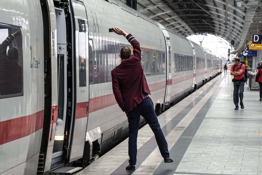 Ein Zugbegleiter zeigt das Signal zur Abfahrt