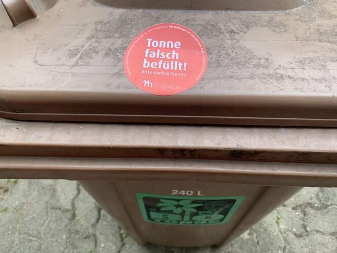 Geschlossene braune Tonne mit Sticker "Tonne falsch befüllt! Bitte nachsortieren"