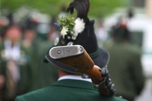 Ein Mann in Tracht trägt ein Gewehr auf der Schulter