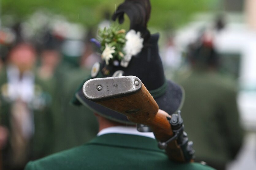 Ein Mann in Tracht trägt ein Gewehr auf der Schulter