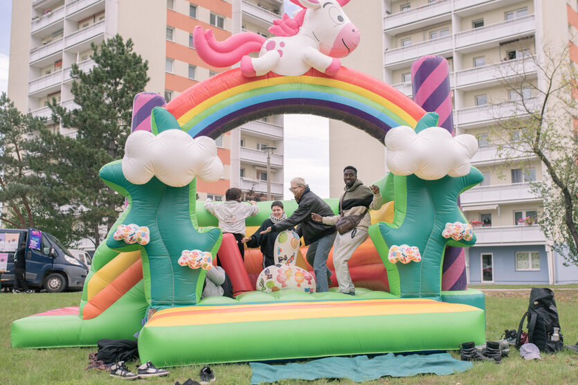 Teilnehmer:innen der Karawane in Eisenhüttenstadt auf einer Hüpfburg mit Regenbogen und Einhorn