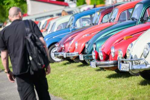 Ein Mann läuft an einer Reihe von VW-Käfern entlang