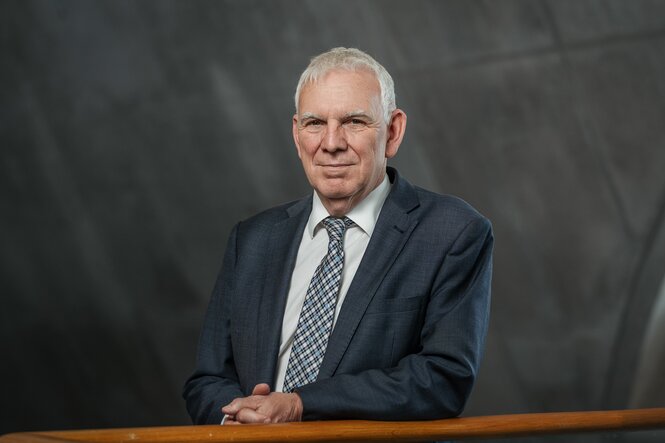 „Porträt von Jochen Flasbarth, Staatssekretär im Bundesumweltministerium, im Anzug mit Krawatte. Er steht vor einem neutralen, dunklen Hintergrund und blickt in die Kamera."