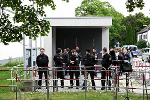 Polizisten stehen hinter Absperrgittern