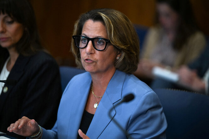 Lisa Monaco hat dunkelblonde Haare, sie trägt ein blaues Sakko und eine schwarzgerahmte Brille