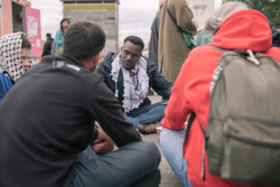 Mehrere Menschen sitzen auf dem Boden und diskutieren