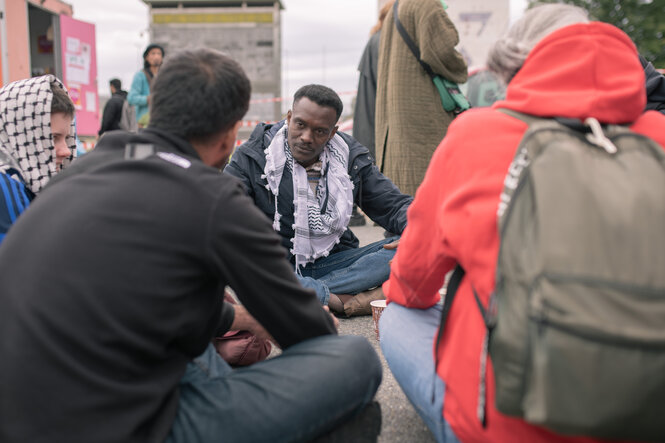 Mehrere Menschen sitzen auf dem Boden und diskutieren