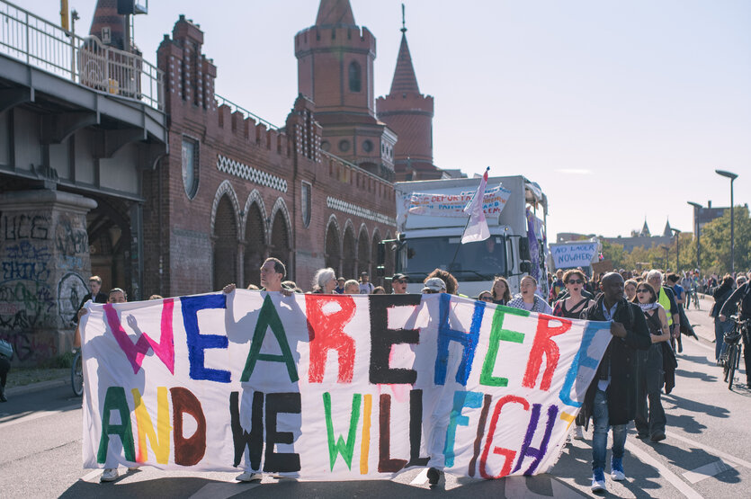 Menschen mit Plakat mit der Aufschrift "We are here and we will fight"