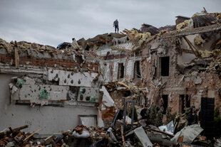 Ein Mann steht auf dem Dach eines zerstörten Wohnhauses in Kyiv