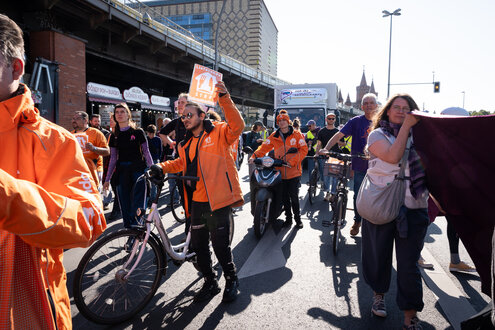 Lieferando-Kuriere in orange-farbenen Uniformen protestieren vor der Konzernzentrale in Kreuzberg