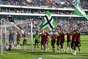 Hannovers Spieler stehen nach dem Spiel vor der Fankurve und jubeln.