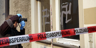 Ein Fotograf dokumentiert ans Fenster gemalte Hakenkreuze