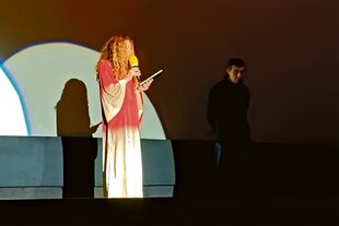 Auf einer Bühne beim Hamburger Filmfest in einem Lichtkegel steht die Journalistin Alena Jabarine daneben im Dunkel der Regiesseur Fatih Akin