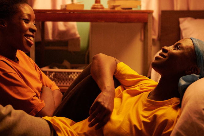 Ein Standbild in Sepia aus dem Film "Dreamers", in dem zwei Personen auf einer Couch sitzen und versonnen lachen.